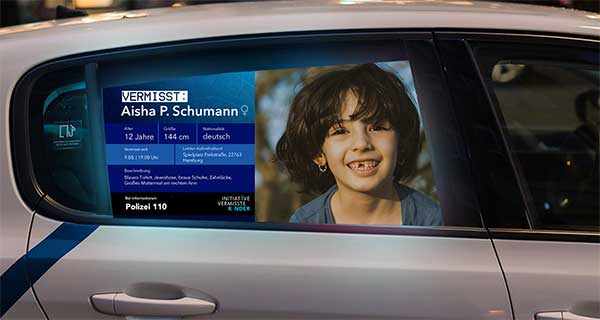 Bildschirm in einem öffentlichen Verkehrsmittel zeigt eine digitale Vermisstenmeldung mit Foto und Details.
